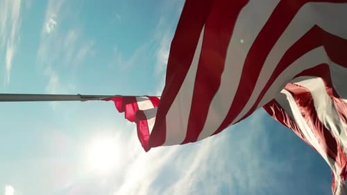 American Flag Waving Against Blue Sky with Sun