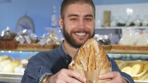 Man Holding Bread in Bakery Shop