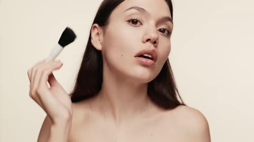 Woman Applies Makeup with Brush and Smiles