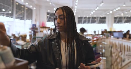 Young Female Shopper with Smart Phone Browsing in Craft Store 10 Seconds or Greater