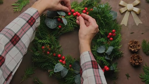 Hands Arranging Berries on a Christmas Wreath