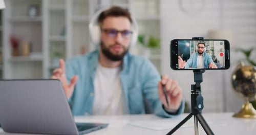 Focus on Screen of Smartphone. Young Man is Live Streaming a Training Blog at Home. Blogger