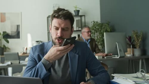 Businessman Talking on Mobile Phone in Speaker Mode during Office Workday