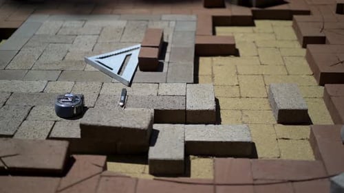 Construction zone detail of brick paver custom emblem in herringbone pattern.