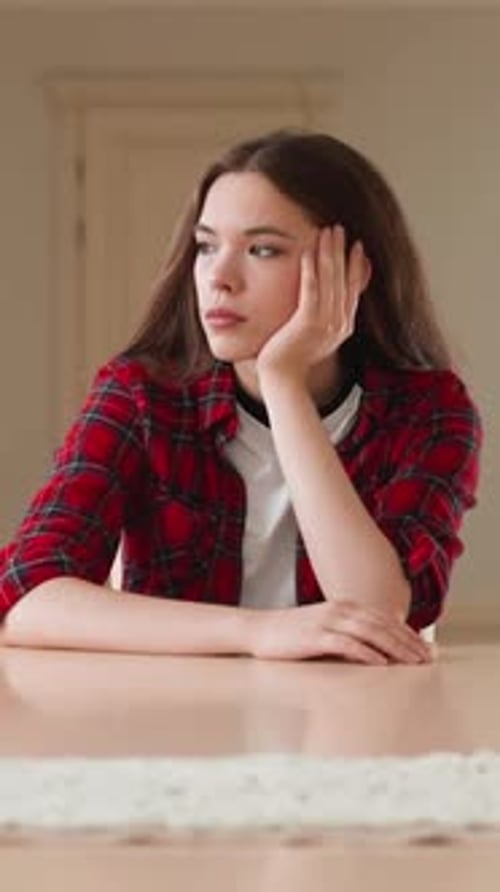 Young Woman Sitting Thoughtfully At Table Indoors