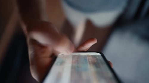 Nahaufnahme einer Hand, die einen Social Media-Feed auf einem Smartphone scrollt