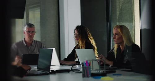 Smiling male employee works on laptop during relaxed office meeting while