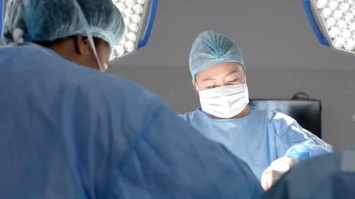 Diverse female surgeons operating on patient in operating theatre, slow motion
