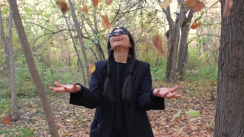 Woman Throws Autumn Leaves in the Forest
