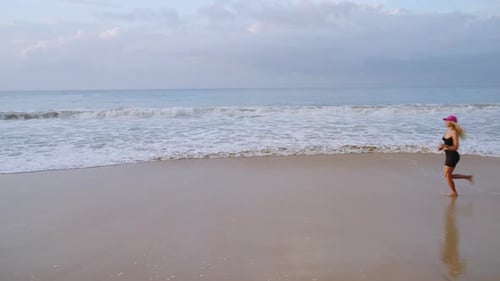 Young Blonde Woman Jogs By Sea at Sunrise Caucasian Female Runs on Beach By Ocean at Dusk Fit Sporty