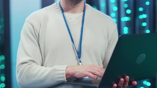 A Focused Man Works on a Laptop in a Hightech Server Room