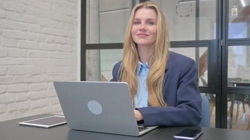 Smiling Woman Working on Laptop in Office