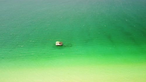 Luftbild einer schwimmenden Hütte im tropischen türkisblauen Meerwasser