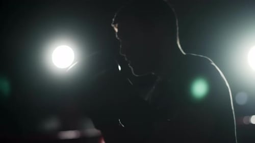 Exercise in an Indoor Gym A Man Hits His Opponent with Hard Blows A Dark Room a Silhouette of a