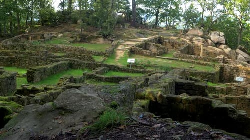 Ruines en pierre du complexe archéologique de Castro Cibdá de Armeá, entourées d'arbres, Orense