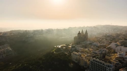 Drone shot flying towards Mellieha Church on a hill in a heavily misty morning in Malta