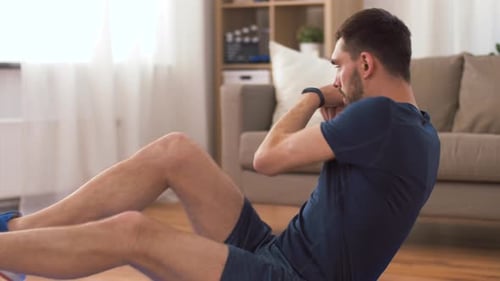 Man exercising abdominal muscles inside in a living room