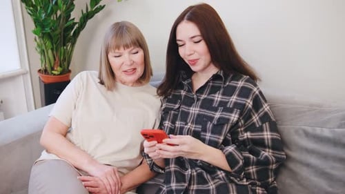 Woman showing adult mother how to use phone