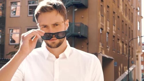 Man Takes Off Sunglasses and Smiles