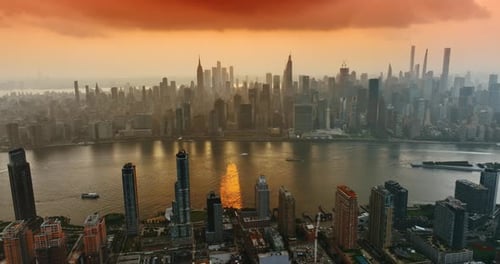 Amazing orange cloudscape above the Hudson River. Majestic skyscrapers of New York