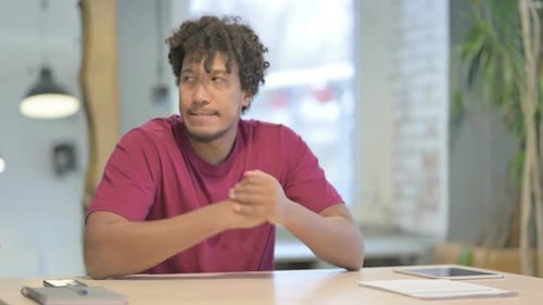 Young Adult Man Sitting at Desk Looking Upset