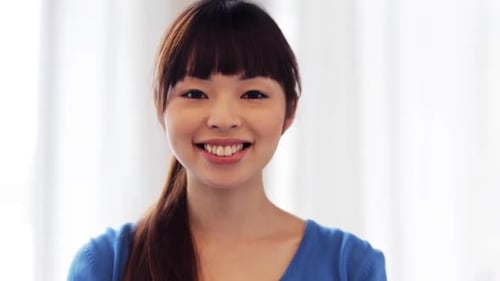 Smiling young woman looks directly at camera indoors
