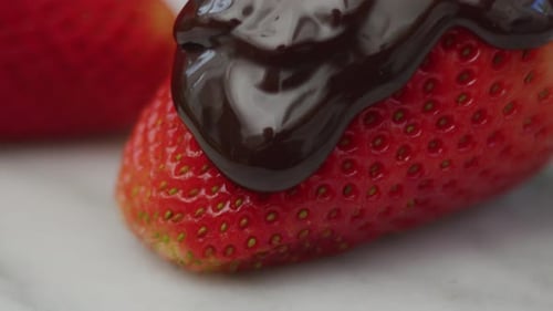 Close-Up of Chocolate Pouring Onto Strawberry. with Red Camera