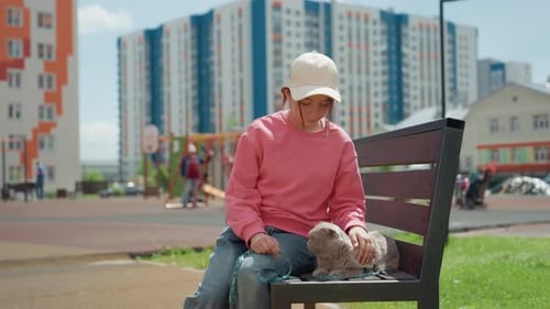 Child Sits Alone On Bench With Dog Beside Them Contemplative Moment In Urban Park With Highrise