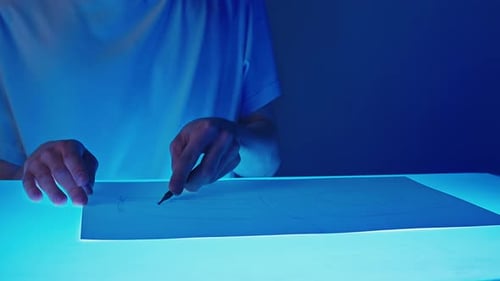 Artist Drawing with Pencil on Illuminated Table
