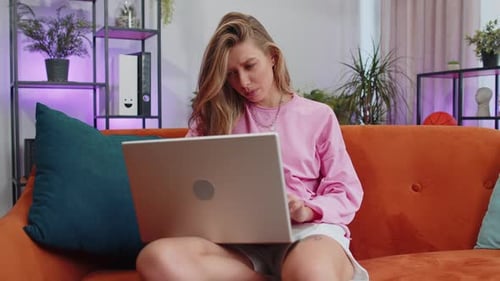 Young Woman Using Laptop on Orange Couch