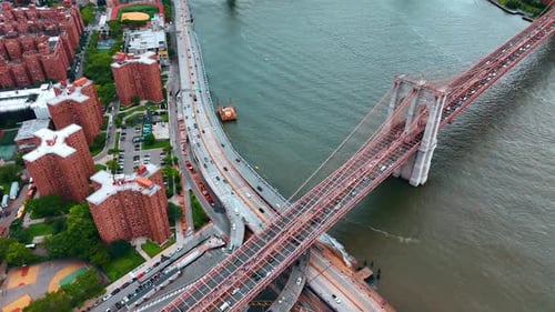 Multiple cars ride quickly by the highways along the East River and by the Brooklyn Bridge.