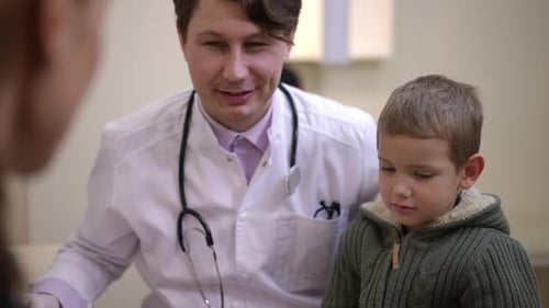 Portrait of Cute Little Boy Talking Sitting on Lap of Doctor with Unrecognizable Woman at Front