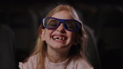 Joyful Child Laughing in Movie Theater with 3D Glasses