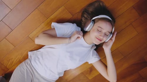 Woman Listening to Music with Headphones on Floor