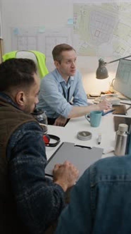 Ingenieros civiles discutiendo planos en una computadora en una oficina de construcción