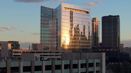 A zoomed in drone shot with parallax decreasing elevation and centered on a parking garage and a bui