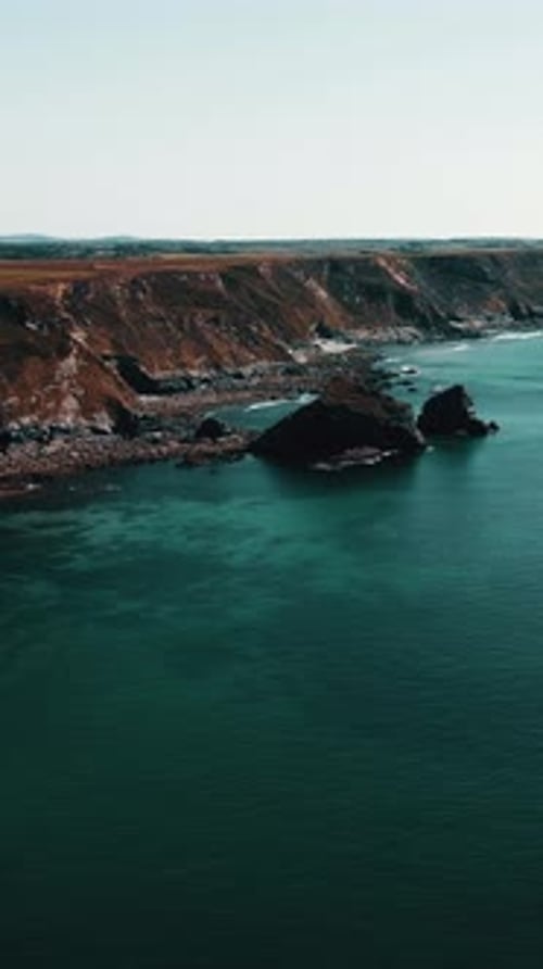 Rocks off the ocean coast line with turquoise water Vertical video