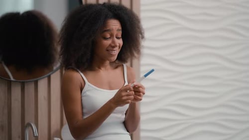 Young Woman with Pregnancy Test in Bathroom
