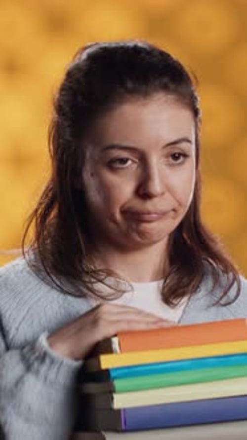 Vertical Video Sulky Lady with Stack of Novels Doing Thumbs Down Hand Gesturing