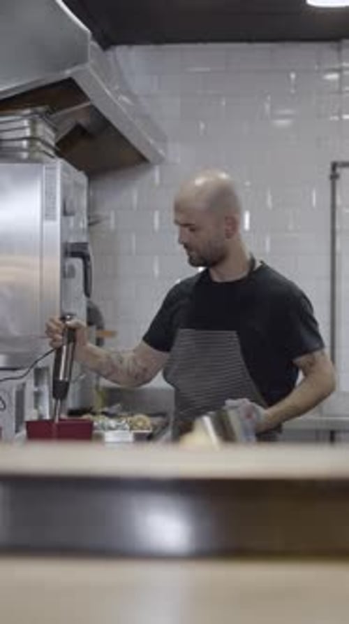 Male Chef Works in Restaurant Kitchen Blurry Objects in Foreground