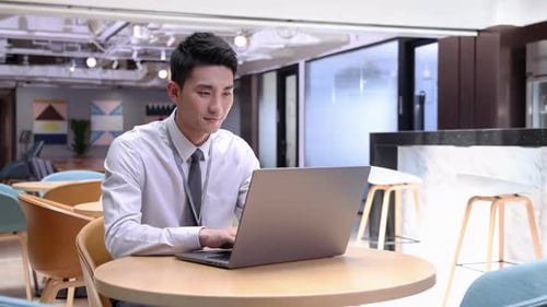 Focused Young Man Works on Laptop in Office