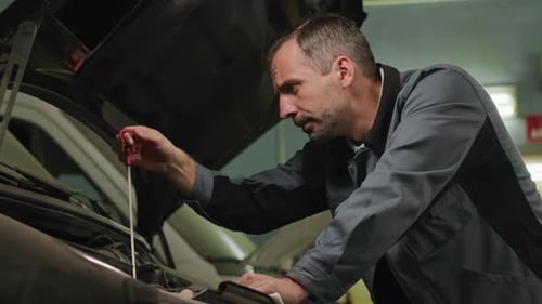 Mann repariert Auto in Autowerkstatt