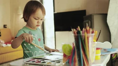 Child Painting with Watercolors at Table Indoors