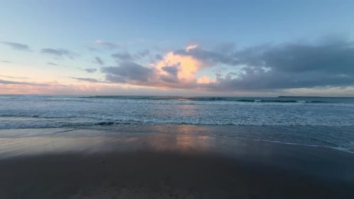 Ruhige Sonnenuntergangswellen an einem leeren Strand
