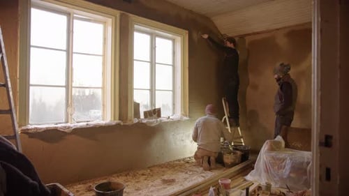 Workers Plastering Walls in House Under Construction