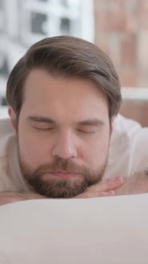 Erwachsener Mann schläft, während er auf dem Bauch im Bett liegt, vertikal