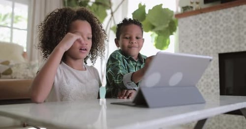 Children Interact with Tablet Device at Table Indoors