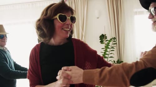 Cheerful seniors dance at a party in home