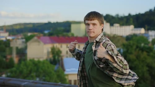 Kaukasischer gutaussehender Tänzer, der draußen auf dem Dach Hip Hop aufführt, brünetter Mann, der tanzt