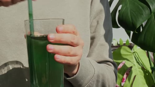 Unrecognizable Woman Drinking Natural Organic Green Spirulina Algae Powder Drink on Neutral Beige